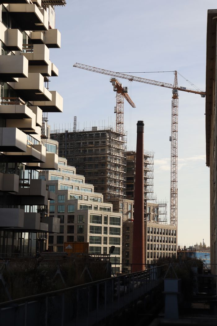 Modern urban construction site with cranes and unique architecture against a clear sky.